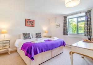 a bedroom with a bed with purple sheets and a window at The Little Barn in Felbrigg