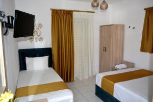 Habitación de hotel con 2 camas y TV en Chrissi Ammoudia, en Toroni