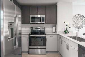 a kitchen with stainless steel appliances and wooden cabinets at Dahlia - The Designer Townhome in Lake Worth