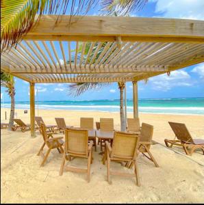 a table and chairs on a beach with the ocean at Hard Rock at Cana Rock 1 by Unwind Properties in Punta Cana