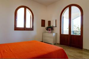 una camera con un letto arancione e due finestre di Villa Panoramica sul Mare a Valderice