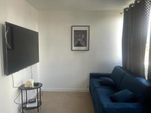 a living room with a blue couch and a tv at Joli studio entre Paris et Disneyland in Villemomble