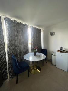 ein Wohnzimmer mit einem Tisch und einem blauen Stuhl in der Unterkunft Joli studio entre Paris et Disneyland in Villemomble + 4 Fotos