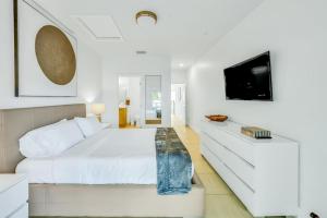 - une chambre blanche avec un grand lit et une télévision dans l'établissement Lilly at Aviara Lake Worth, à Lake Worth
