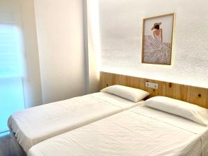 2 camas en un dormitorio con una foto en la pared en Apartamento con 3 habitaciones, terraza y jardin comunitario con piscina en Sant Antoni de Calonge, en Sant Antoni de Calonge