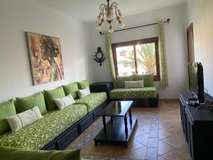 a living room with green couches and a tv at Mi Casa Jardins de Cabo Negro in Cabo Negro