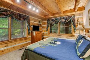 a log cabin bedroom with a bed and windows at Smokies Sanctuary in Hatchertown