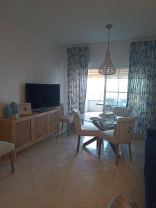 a living room with a television and a table and chairs at ADNANIa 2023 in La Herradura