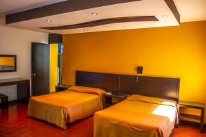 2 camas en una habitación de hotel con paredes amarillas en Hotel Villa Capri en Morelia
