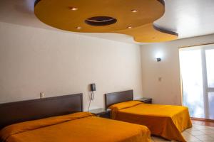 1 dormitorio con 2 camas con sábanas de color naranja y techo en Hotel Villa Capri en Morelia