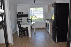 a kitchen with a white table and a black refrigerator at Apartament Zacisze in Iława