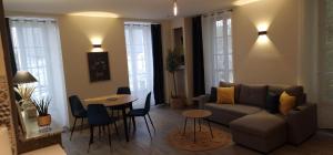 a living room with a couch and a table and chairs at Au pied de Sancerre logement Cosy in Saint-Satur +4 photos