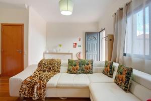 a living room with a white couch with leopard pillows at Moradia Casa Feliz in Santa Cruz