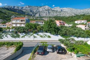 a group of cars parked in a parking lot with mountains at Apartments Marsela in Tučepi