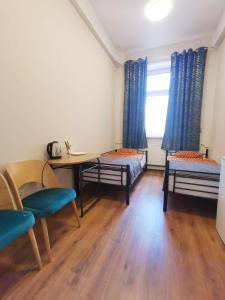 a room with a table and two beds and a window at Hostel KASZUBSKA in Wrocław