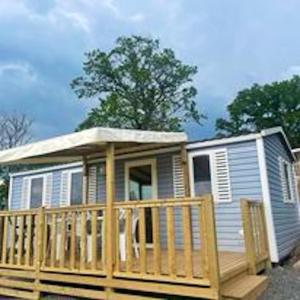 una casa pequeña con porche y terraza en Bungalow de 3 chambres avec piscine partagee terrasse amenagee et wifi a Argences en Aubrac, en Banes