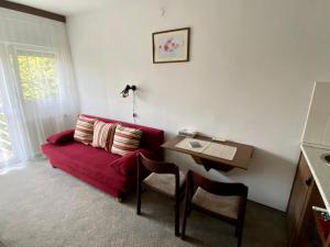 uma sala de estar com um sofá vermelho e uma mesa em Veronika Apartman em Balatongyörök