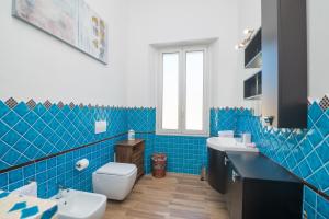 bagno piastrellato blu con servizi igienici e lavandino di Maison Chloe a La Maddalena Altre 17 foto