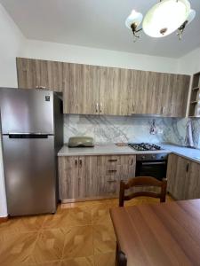 La cuisine est équipée d'un réfrigérateur en acier inoxydable et de placards en bois. dans l'établissement Apartment Kune, Shëngjin 2, à Shëngjin