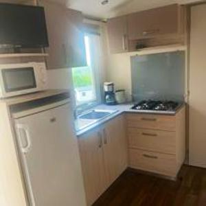 a small kitchen with a stove and a microwave at Bungalow charmant à Argences en Aubrac avec piscine in Banes