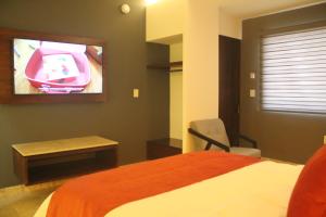 - une chambre avec un lit et une télévision murale dans l'établissement Hotel veinti 3 Tapachula, à Raymundo Enríquez