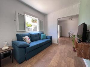 Una sala de estar con un sofá azul y un televisor. en Villa Almagre, en Gáldar