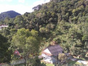 uma casa no lado de uma colina com árvores em QUARTO CASA FREDERICO em Domingos Martins