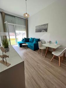 a living room with a blue couch and a table at Bala Beach Siófok Apartman in Siófok