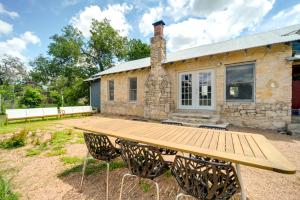 a wooden picnic table in front of a stone house at Rural Texas Vacation Rental with Fireplace in Dripping Springs