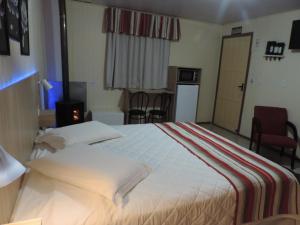 a hotel room with a large bed and a kitchen at Cabanas Costaneira in Cambará