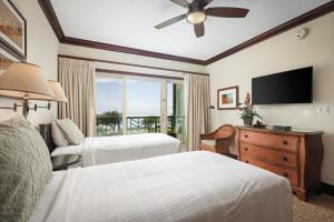 a hotel room with two beds and a flat screen tv at Waipouli Beach Resort and Spa Kauai by OUTRIGGER in Kapaa