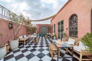 un patio con mesas y sillas en un suelo a cuadros en Riad Appart Arwa, en Marrakech
