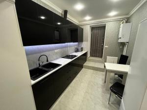 a kitchen with black cabinets and a sink and a table at Central Charm Guesthouse in Gyumri
