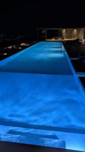a large swimming pool lit up blue at night at Sunset Hill Suites in Mýkonos City