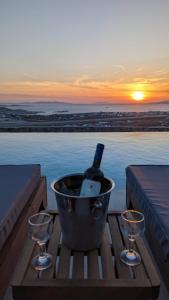 Sunset Hill Suites في مدينة ميكونوس: دلو مع زجاجة من النبيذ وكأسين من النبيذ
