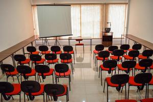 ein Zimmer mit einem Klassenzimmer mit Stühlen und einem Bildschirm in der Unterkunft Hotel Nações in Presidente Prudente