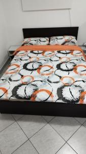 a bed with an orange and black comforter on it at Apartma B & O in Idrija