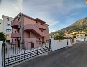 a pink house with a fence in front of it at Apartments Normannia in Dobra Voda