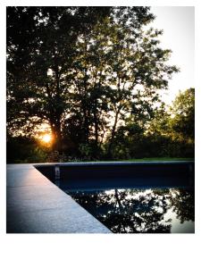 une piscine d'eau avec un arbre et le coucher du soleil dans l'établissement Nonpareil, à Peyrat-la-Nonière