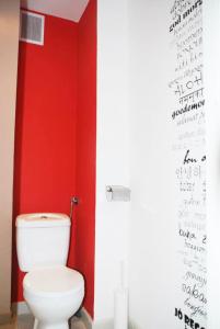 a bathroom with a white toilet in a red wall at Apartament Centrum in Szczecinek