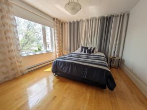 1 dormitorio con cama y ventana grande en Le Cocon du Rivage, en Roberval