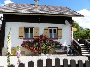 una pequeña casa con un banco y flores delante en Knusperhaus en Strobl