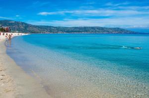 a beach with people walking on the sand and the water at Il Nocchiero City Hotel in Soverato Marina
