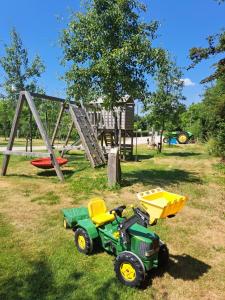 een groene en gele speelgoedtractor en een speeltuin bij De Weitens Valkenswaard in Valkenswaard