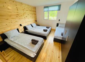 two beds in a room with a wooden wall at CozyHut Бунгало под Наем in Chernomorets