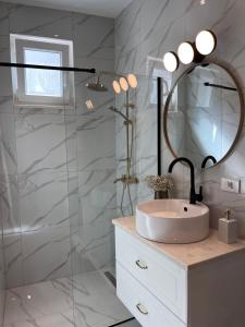 y baño con lavabo y ducha con espejo. en Modern Apartment Olive 30 Meters From The Beach in Duce en Duće