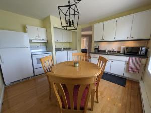 a kitchen with a table and chairs and white cabinets at Le Cocon du Rivage in Roberval