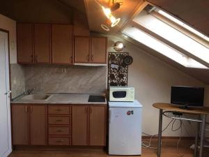 an attic kitchen with a refrigerator and a microwave at Бижу в сърцето на Варна in Varna City