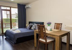 a bedroom with a bed and a wooden table and chairs at Balchik Garden Palace - 2BD Flat in Balchik