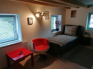 a bedroom with a bed and a red chair at Zum Pfarrberg in Meerane